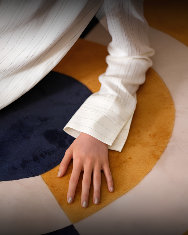 Hand resting on the soft pile of a navy and gold carpet